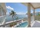 Balcony showcasing a stunning view of the ocean, swimming pool, and lush tropical landscaping at 585 Gunwale Ln, Longboat Key, FL 34228