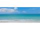 Calm beach with gentle waves lapping the shore under a sunny sky with fluffy white clouds at 585 Gunwale Ln, Longboat Key, FL 34228