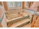 A tiled bathtub with spa jets is decorated with ocean accessories, under a shuttered window for natural light at 701 Marbury Lane, Longboat Key, FL 34228