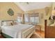 Bright bedroom featuring a white bed frame, wood floors, tropical decor, and natural light from shuttered windows at 701 Marbury Lane, Longboat Key, FL 34228