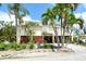 Charming yellow two-story home with lush landscaping, palm trees, and a welcoming entrance at 701 Marbury Lane, Longboat Key, FL 34228