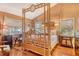 Bright and airy bedroom with unique bamboo canopy bed, wood floors, and ample natural light from surrounding windows at 701 Marbury Lane, Longboat Key, FL 34228