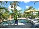 A backyard pool is surrounded by lush landscaping and a stone patio under a sunny sky, creating a private oasis at 701 Marbury Lane, Longboat Key, FL 34228