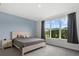 Cozy bedroom featuring a large window, soft blue accent wall, and natural wood furniture at 9291 Starry Night Ave, Sarasota, FL 34241