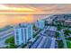 Aerial view of condos, the beach, a tennis court, covered parking, and a beautiful ocean sunset at 1000 Longboat Club Road # 1105, Longboat Key, FL 34228
