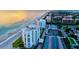 Gorgeous sunset aerial view of beachfront condos with lush landscaping and community amenities like tennis courts at 1000 Longboat Club Road # 1105, Longboat Key, FL 34228
