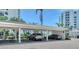 Covered carport featuring multiple parking spaces with well-maintained landscaping and building in the background at 1000 Longboat Club Road # 1105, Longboat Key, FL 34228