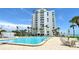 An inviting pool area next to a white condominium building and palm trees at 1000 Longboat Club Road # 1105, Longboat Key, FL 34228