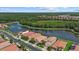 Aerial view of a community with a lake featuring a fountain, surrounded by lush greenery and well-kept residences at 11550 Blackfin St, Venice, FL 34292