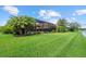 Spacious backyard with a screened-in lanai, lush green grass, mature landscaping, and a tranquil lake backdrop at 11550 Blackfin St, Venice, FL 34292