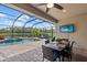 Screened pool area with patio dining, lounge chairs, and a scenic view of the water and natural landscape at 11550 Blackfin St, Venice, FL 34292