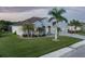 Beautifully landscaped home featuring a paver driveway, a three-car garage, and mature palms in a serene setting at 15808 42Nd E Gln, Parrish, FL 34219