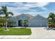 Charming single-story home featuring a lush lawn, mature palms, a paver driveway, and a three-car garage at 15808 42Nd E Gln, Parrish, FL 34219