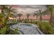 Community hot tub surrounded by lush landscaping, lounge chairs, umbrellas, and palm trees at 16415 Star Grass Cir, Bradenton, FL 34211