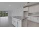 Spacious kitchen with white cabinets, granite island, and view of living area and outdoor scenery at 18068 Cherished Loop, Bradenton, FL 34211