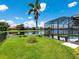 Expansive backyard featuring a screened pool enclosure, a tranquil lake view, and vibrant green grass at 280 Dahlia Ct, Bradenton, FL 34212