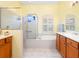 A clean bathroom featuring tile floors, a walk-in shower, soaking tub, and wood cabinetry offering plenty of storage space at 280 Dahlia Ct, Bradenton, FL 34212