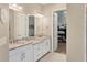 Elegant bathroom with dual sinks, granite countertops, and a view into the walk-in closet at 5596 Cantucci St, Nokomis, FL 34275