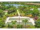 Aerial view of bocce ball courts surrounded by lush landscaping, a walking path, and a tranquil lake at 5596 Cantucci St, Nokomis, FL 34275