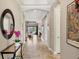 Long hallway featuring tiled floors, arched doorways, tray ceilings, and neutral paint throughout at 5596 Cantucci St, Nokomis, FL 34275