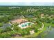 Aerial view of a community pool area with lush landscaping, tennis courts and clubhouse in residential neighborhood at 5596 Cantucci St, Nokomis, FL 34275