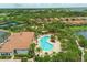 Aerial view of a large community pool with surrounding lounge chairs, landscaping, and tennis courts in a residential neighborhood at 5596 Cantucci St, Nokomis, FL 34275