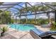 Beautiful pool with a waterfall feature, surrounded by tropical landscaping and comfortable lounge chairs at 5596 Cantucci St, Nokomis, FL 34275