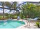 Inviting pool area enclosed with a screen, featuring a waterfall feature and surrounded by lush landscaping at 5596 Cantucci St, Nokomis, FL 34275