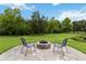 Charming outdoor fire pit area with brick pavers, chairs, and a serene view of the lush green backyard at 731 116Th Ne Ct, Bradenton, FL 34212