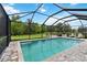 Inviting screened-in pool area with lounge chairs, offering a peaceful retreat overlooking a lush green backyard and pond at 731 116Th Ne Ct, Bradenton, FL 34212