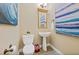 Cozy powder room featuring a pedestal sink, complemented by blue-themed artwork and decor at 7324 Gulf Dr # 12, Holmes Beach, FL 34217
