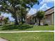 Well-maintained home exterior with mature trees and lush landscaping at 5231 Brassy Loop, North Port, FL 34287