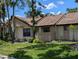 Inviting exterior view of a charming townhome with manicured lawn, mature landscaping and beige facade at 5231 Brassy Loop, North Port, FL 34287