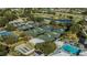 Aerial view of multiple tennis courts, shuffleboard, and a pool nestled within lush landscaping at 802 Montrose Dr # 204, Venice, FL 34293