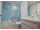 Bathroom featuring light blue tile shower with sliding door, modern marble counter and light wood cabinets at 3006 Caring Way # 325, Port Charlotte, FL 33952