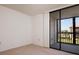 Bright bedroom featuring neutral carpet and walls, with a sliding glass door to balcony overlooking lush greenery at 3006 Caring Way # 325, Port Charlotte, FL 33952