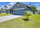 A two-car garage with neutral paint, a long driveway, and a well-manicured lawn featuring a young palm tree at 3482 Dunkirk St, Port Charlotte, FL 33980