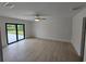 A bedroom with a ceiling fan, light hardwood floors, and glass doors leading to the outside at 8285 Agate St, Port Charlotte, FL 33981