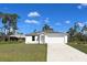 Charming single-story home with a two-car garage and a well-manicured front lawn under a bright blue sky at 13084 Parham Ave, Port Charlotte, FL 33953