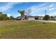 Single-story house with a large front yard, palm trees, and a paved driveway at 176 Jennifer Dr, Rotonda West, FL 33947