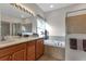 Bright bathroom with double sinks, wood cabinetry, a soaking tub, and a glass enclosed shower at 1712 Lastingham Ln, Port Charlotte, FL 33980