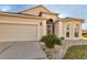 Beige house with a two-car garage, landscaping, and a walkway at 1712 Lastingham Ln, Port Charlotte, FL 33980