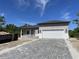 Front view of a single-story house with a white garage door and paver driveway at 14242 Imlay Ave, Port Charlotte, FL 33981
