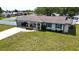 Single-story home with a white brick facade, teal accents, and a well-manicured lawn at 22260 Aburto Ln, Port Charlotte, FL 33952