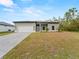 New construction home with a gray exterior, white garage door, and landscaped yard at 12550 Mohican Ave, Port Charlotte, FL 33953