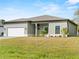 New construction home exterior with a light green facade, white garage door, and landscaping at 12550 Mohican Ave, Port Charlotte, FL 33953