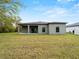 View of the home's rear elevation, showcasing a covered patio and spacious yard at 12550 Mohican Ave, Port Charlotte, FL 33953