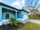 Exterior view of teal house with front porch, garage, and landscaping at 1417 Longson St, Port Charlotte, FL 33953