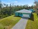Aerial view of a teal home with a paver driveway, and lush green lawn at 1417 Longson St, Port Charlotte, FL 33953
