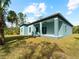 Exterior view of teal house with covered patio and grassy yard at 1417 Longson St, Port Charlotte, FL 33953